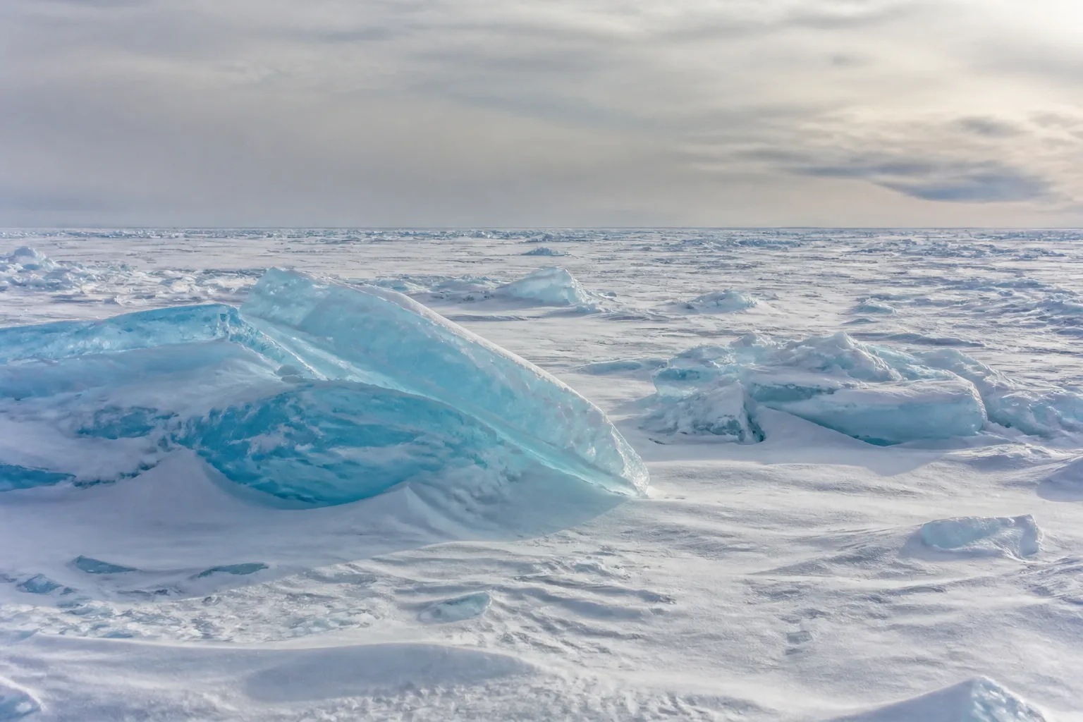 Blue pressure ridges rise above wind-shaped snow on Arctic sea ice.